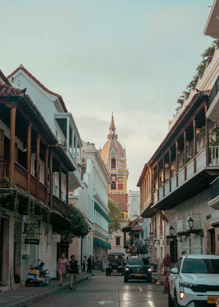 A Cartagena old-town street lined with balconies, leading toward the cathedral tower.